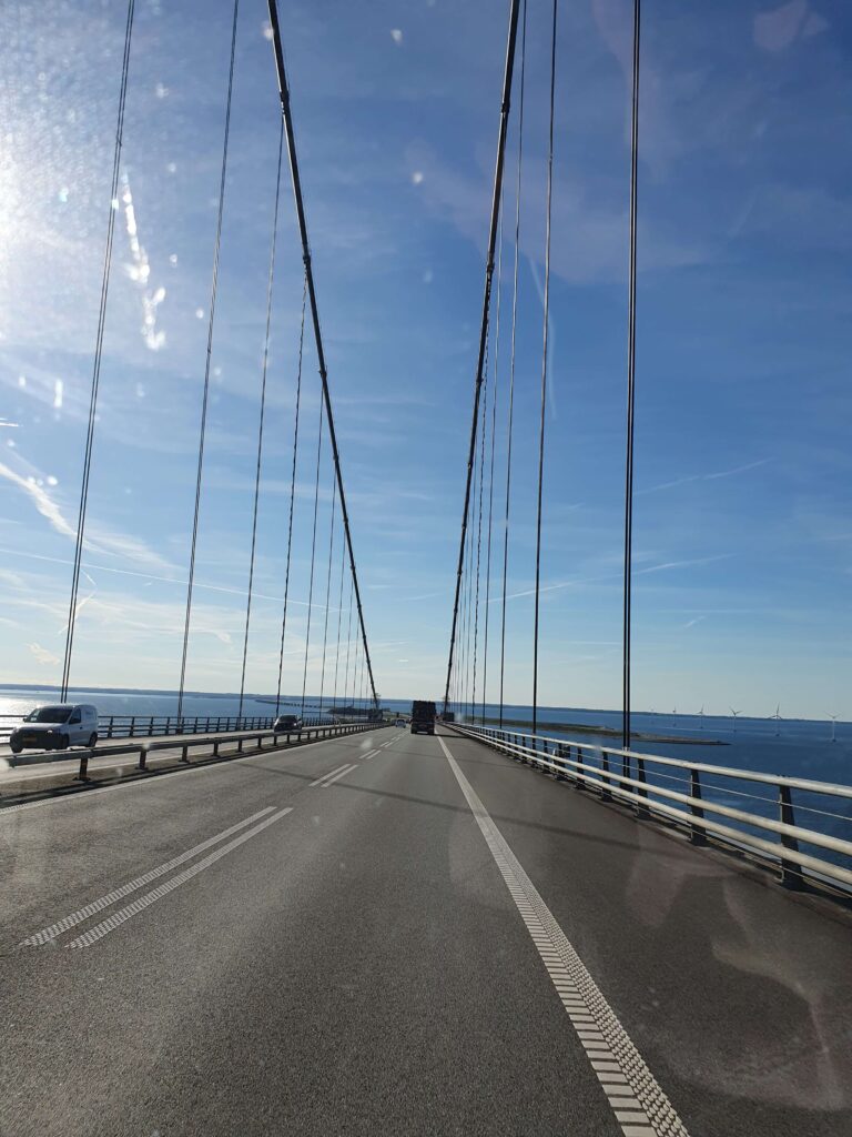 Jacqueline - Reisenbloggerin für Reisen mit Camper und Hund Fahrt über eine Brücke am Meer während einer Reise mit dem Camper. Neuanfang und Freiheit unterwegs. Sonnenschein und wolkenloser Himmel.