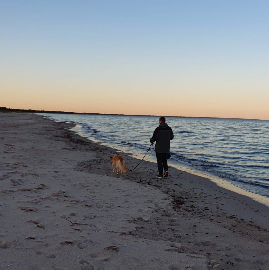 mein Freund am Strand gemeinsam starten wir in unser Leben im Camper. Sonnenuntergang direkt am Meer. Unterwegs mit Hund und Camper.