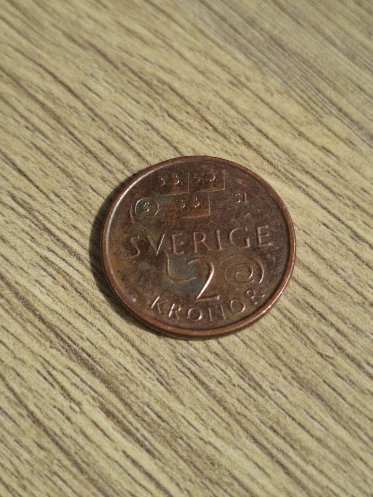 Schwedische 2 Kronen Münze auf einen Holztisch in einem Cafe während unsere Schwedenreis. Die Münze entdeckten wir bei einer Fika und sie gehört zu unseren persönlichen Erinnerungen. Wissenswertes über Schweden.