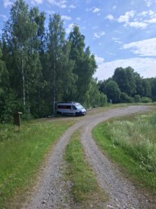 Camper auf einen ruhigen Feldweg zwischen birken und Wiesen während  unserer Reise durch Schweden