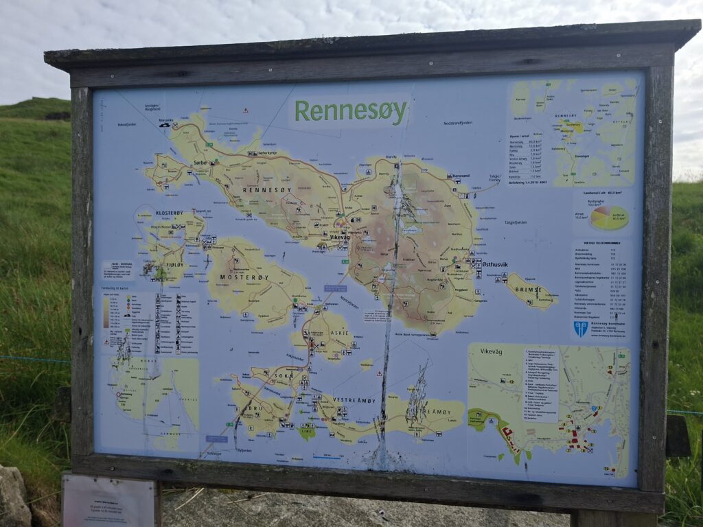 Informationstafel mit einer Karte der Insel Rennesøy, die Besucher bei der Orientierung und Planung von Wanderungen und Aussichtspunkten unterstützt.