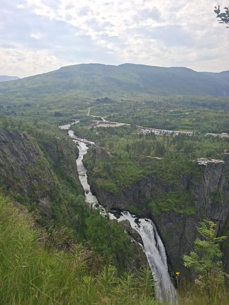 Tiefe Schlucht des Vøringsfossen mit dem Fluss, der sich durch die Felsen schlängelt. Rund um den Wasserfall führen Wanderwege und Aussichtspunkte durch eine beeindruckende Naturlandschaft.