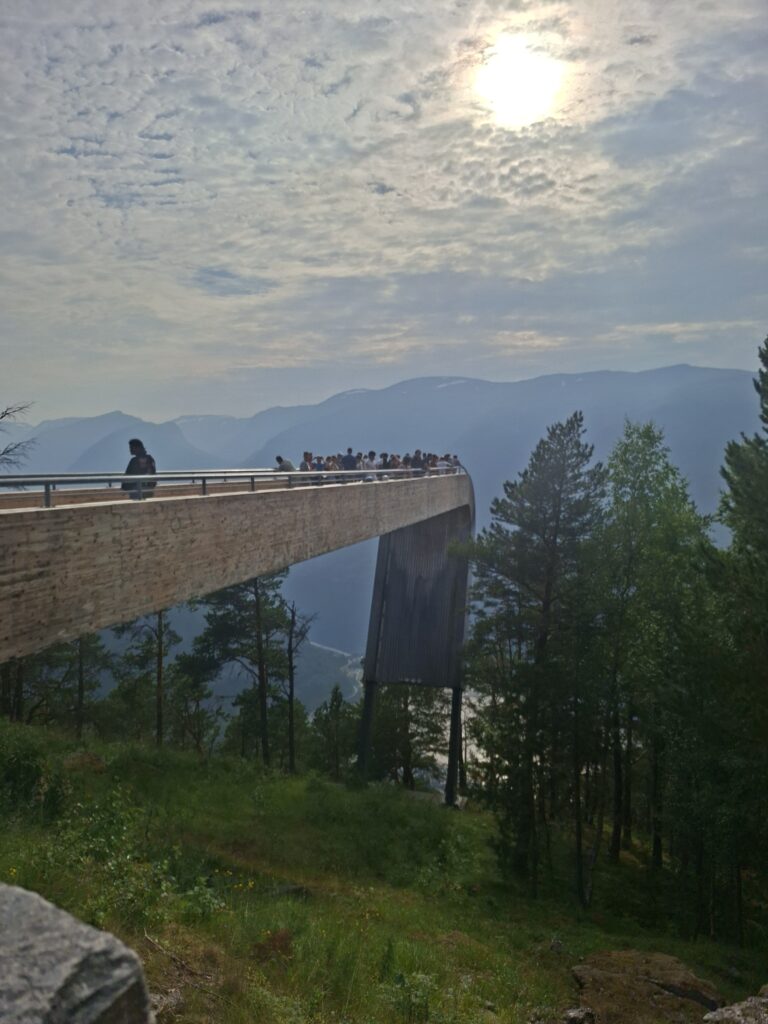 Besucher stehen auf der Stegastein-Aussichtsplattform und blicken über den Aurlandsfjord und die umliegenden Berge. Trotz der beeindruckenden Aussicht war der Aussichtspunkt bei unserem Besuch sehr gut besucht.