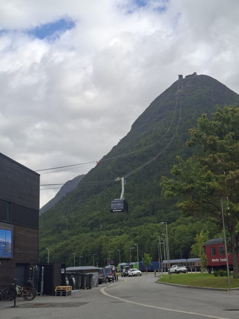 Kleiner norwegischer Ort am Fuße eines steilen Berges mit typischer Bebauung und beeindruckender Bergkulisse.