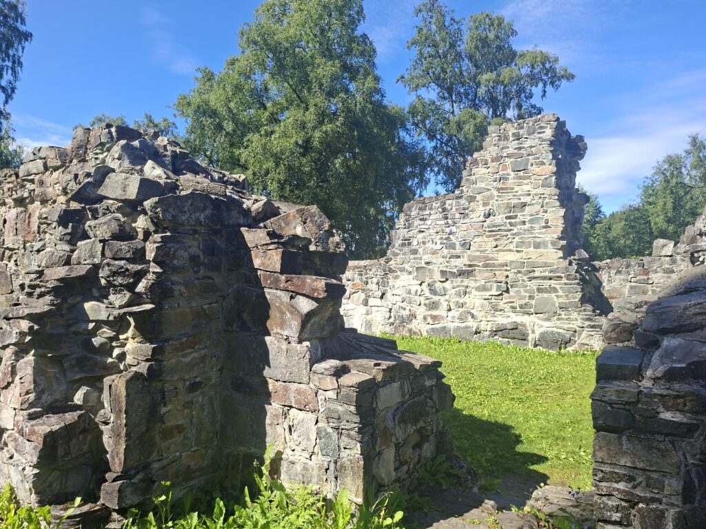 Historische Burgruine aus Naturstein in Norwegen mit erhaltenen Mauern und grünem Innenhof. Solche geschichtsträchtigen Orte zeigen, dass Norwegen weit mehr zu bieten hat als Fjorde und Wasserfälle.