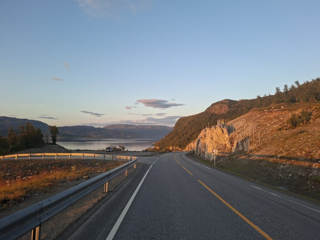 Mittnachtsonne in Norwegen bei unserer Reise durch Norwegen. Das Bild wurde 23.00 aufgenommen. Ein beindruckendes Erlebnis in Norwegen. Im Hintergrund sind Berge und ein Fjord zusehen.