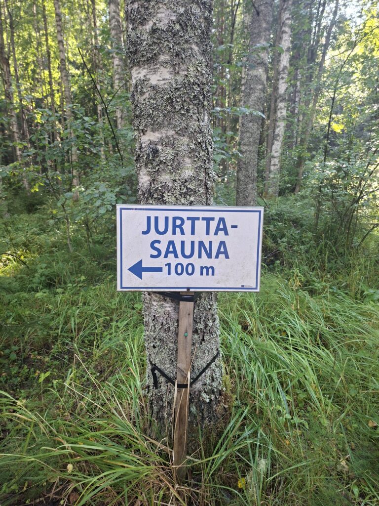 jurttasauna Schild. Das Schild zeigt den Weg zur Sauna in der Natur Finnlands. Das Schild ist weiß mit blauer Aufschrift.